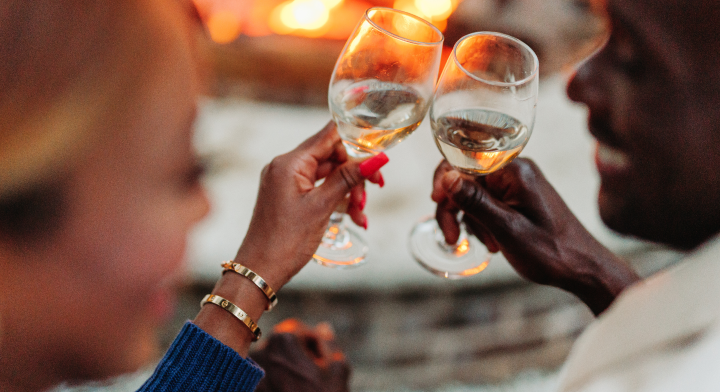 A couple celebrating with wine glasses raised in a toast.