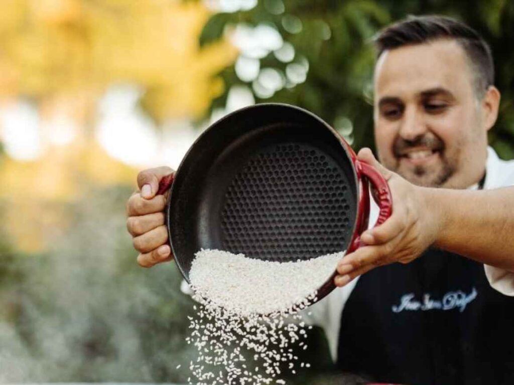 Jose in a chefs apron tossing ingredients in his cooking bowl.